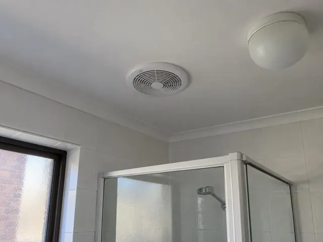 Bathroom ceiling exhaust fan above tiled shower area with white ceiling and window in Beaumont Hills