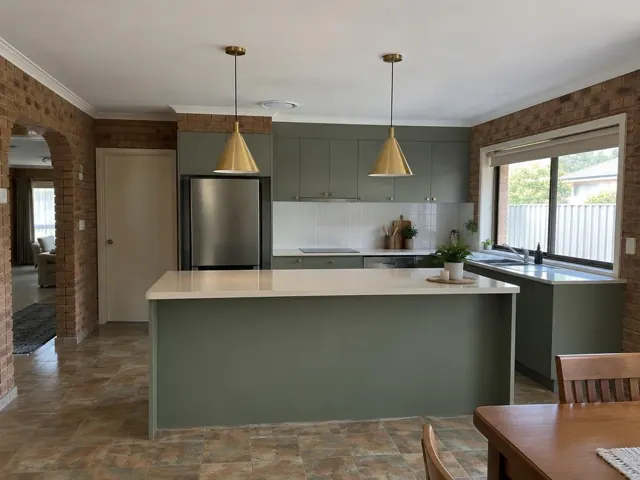 Two brass pendant lights over a kitchen island in a brick-walled home interior in Beaumont Hills